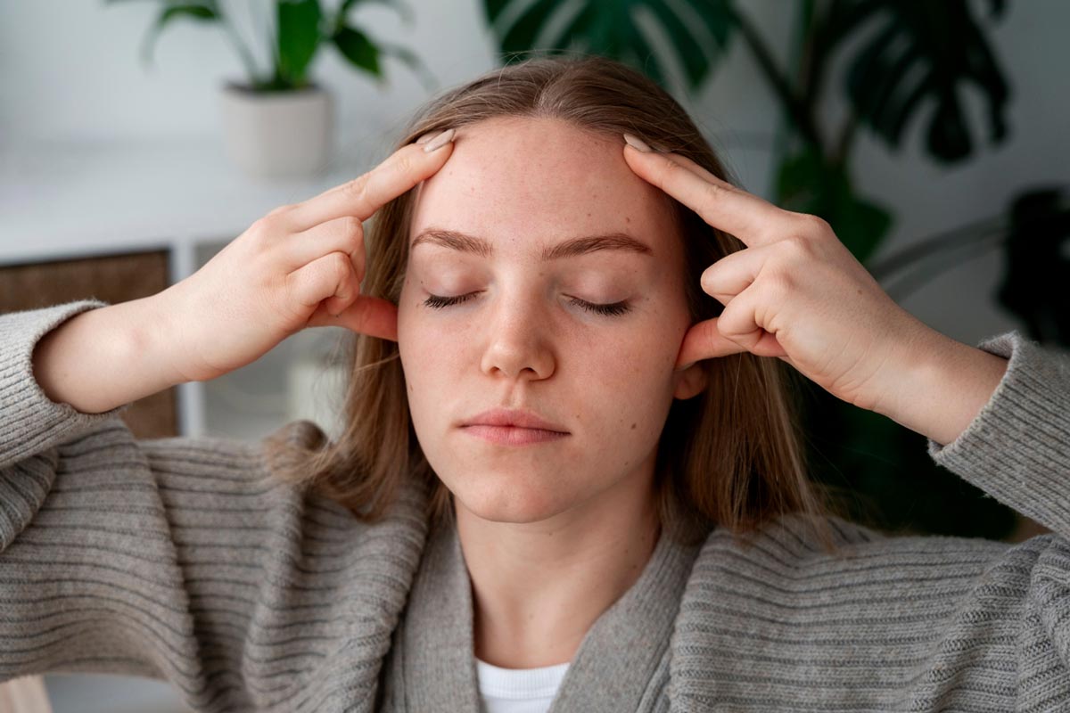 Eine Frau massiert sich die Kopfhaut: Wie Placeboeffekte Kopfschmerz-Therapien verbessern können